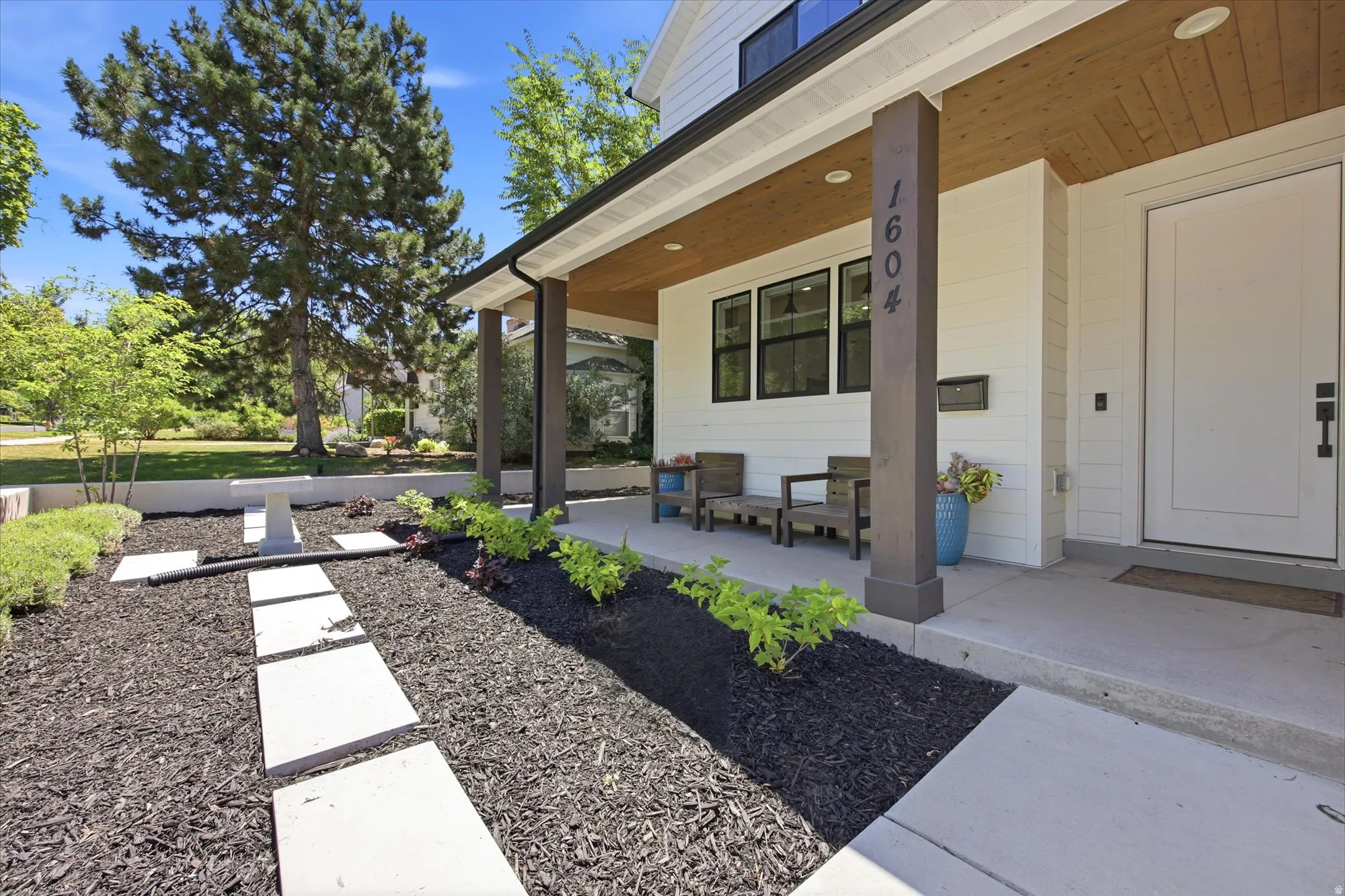 Inviting front porch featuring a wood-finish ceiling, dark-framed windows, and a white entry door
