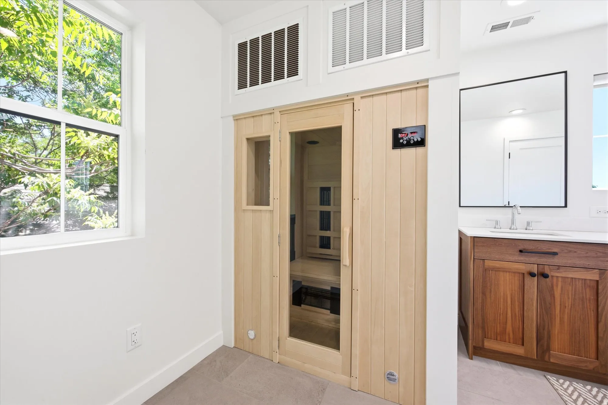 Built-in wood-paneled sauna with a glass door, accompanied by a window offering exterior tree views