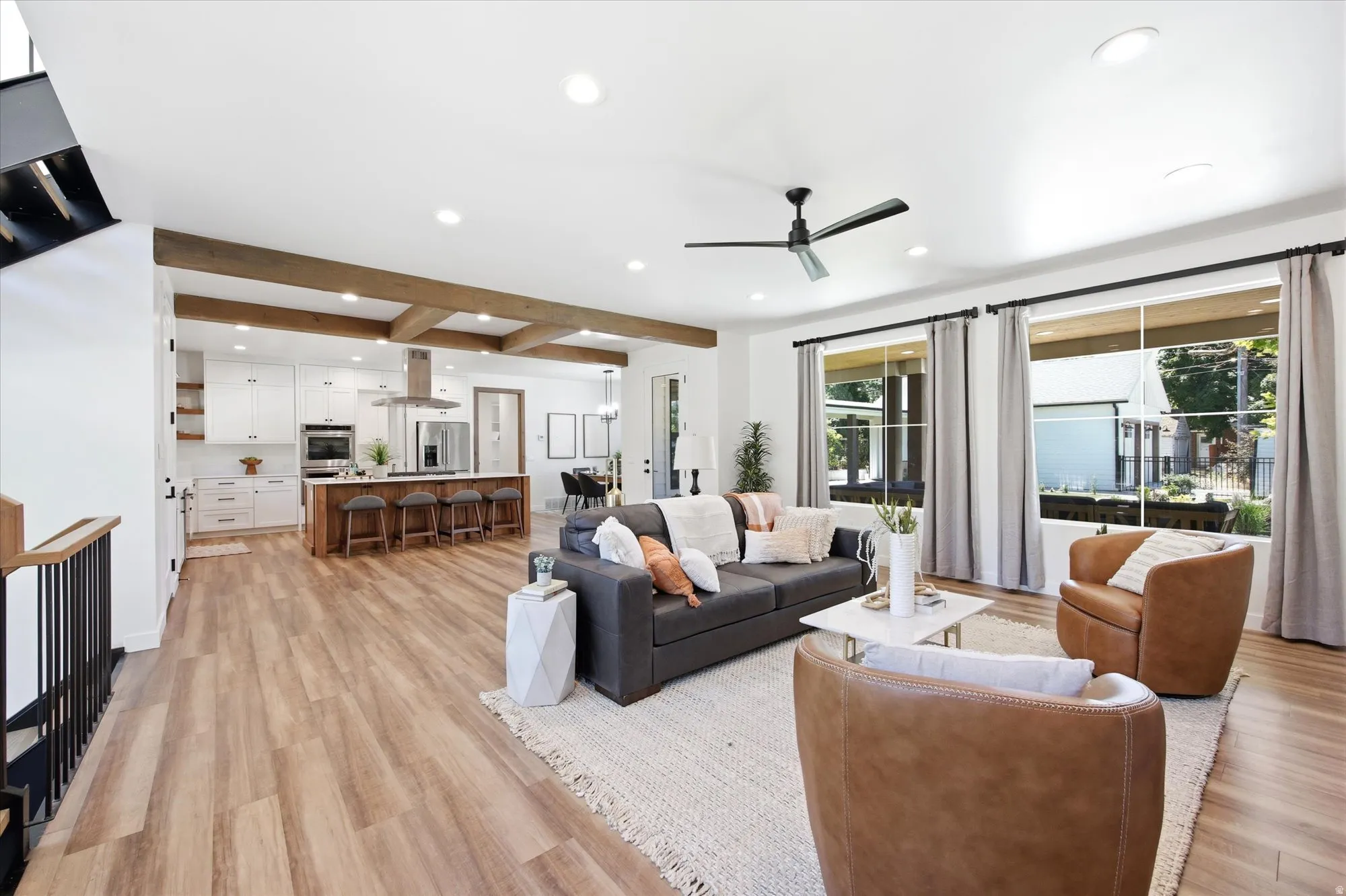 Open-concept living area with wood-finish flooring, recessed lighting, and exposed ceiling beams