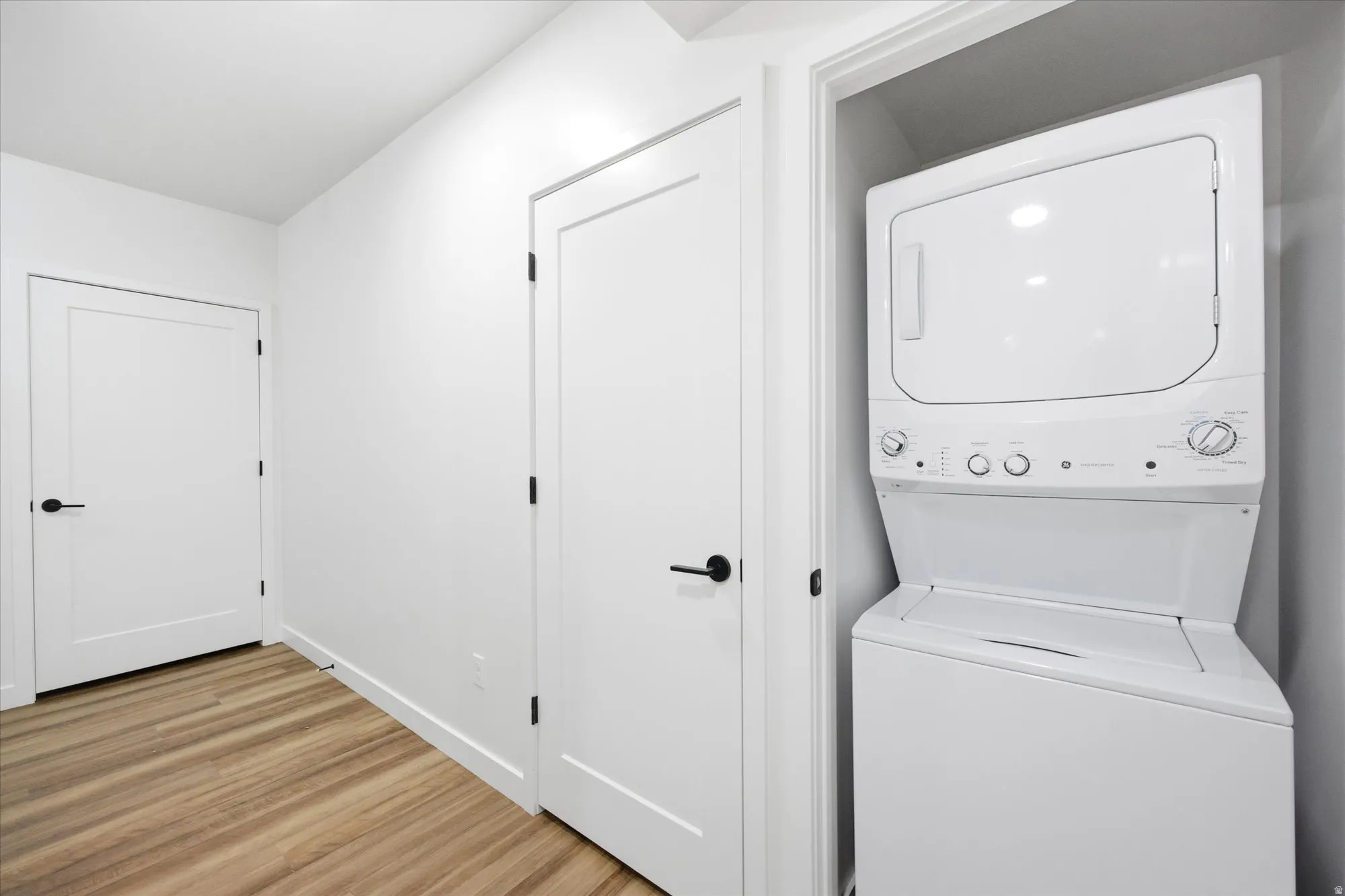 Dedicated laundry closet featuring a white stacked washer and dryer unit