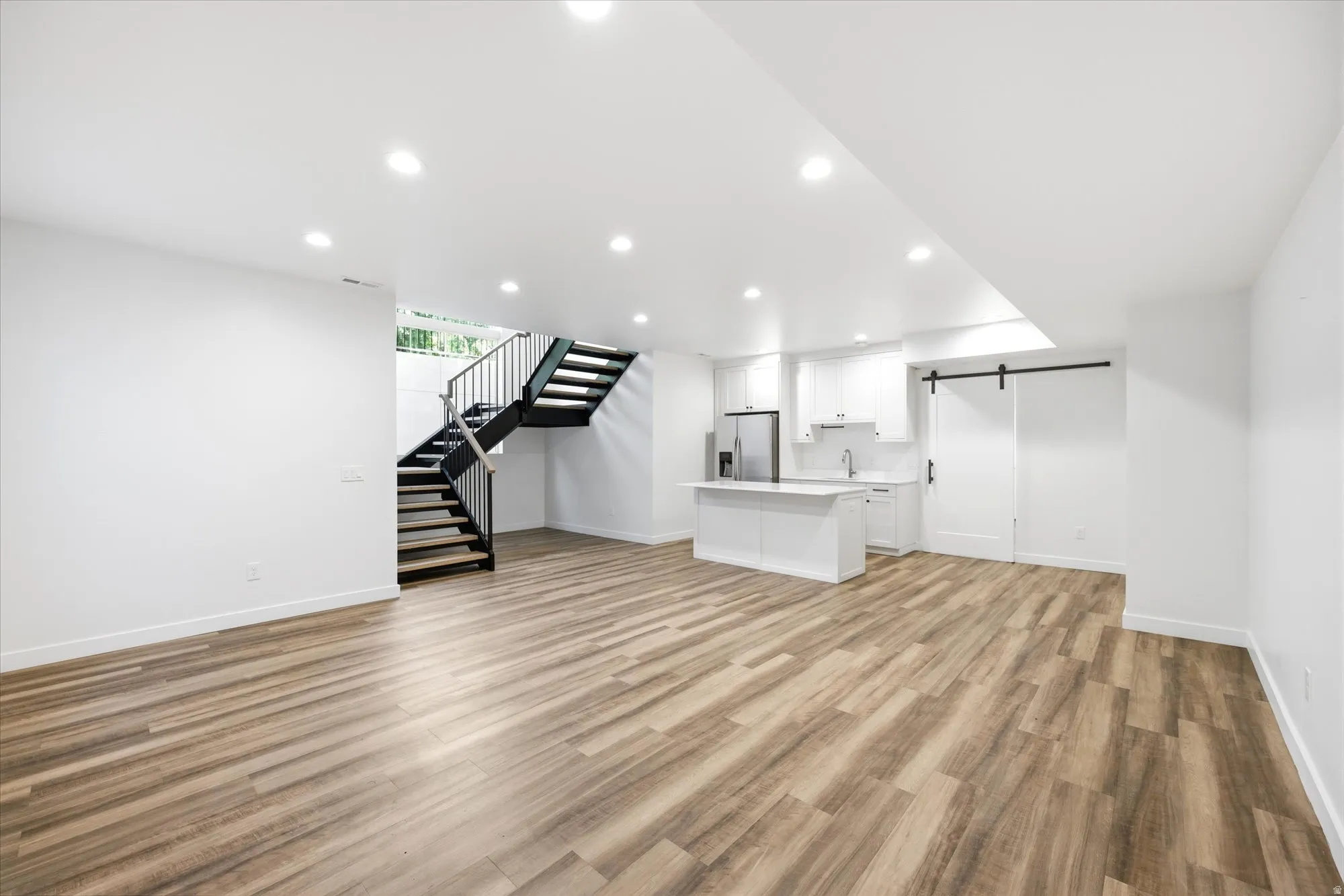 Open-concept living space featuring wood-finish flooring and recessed lighting