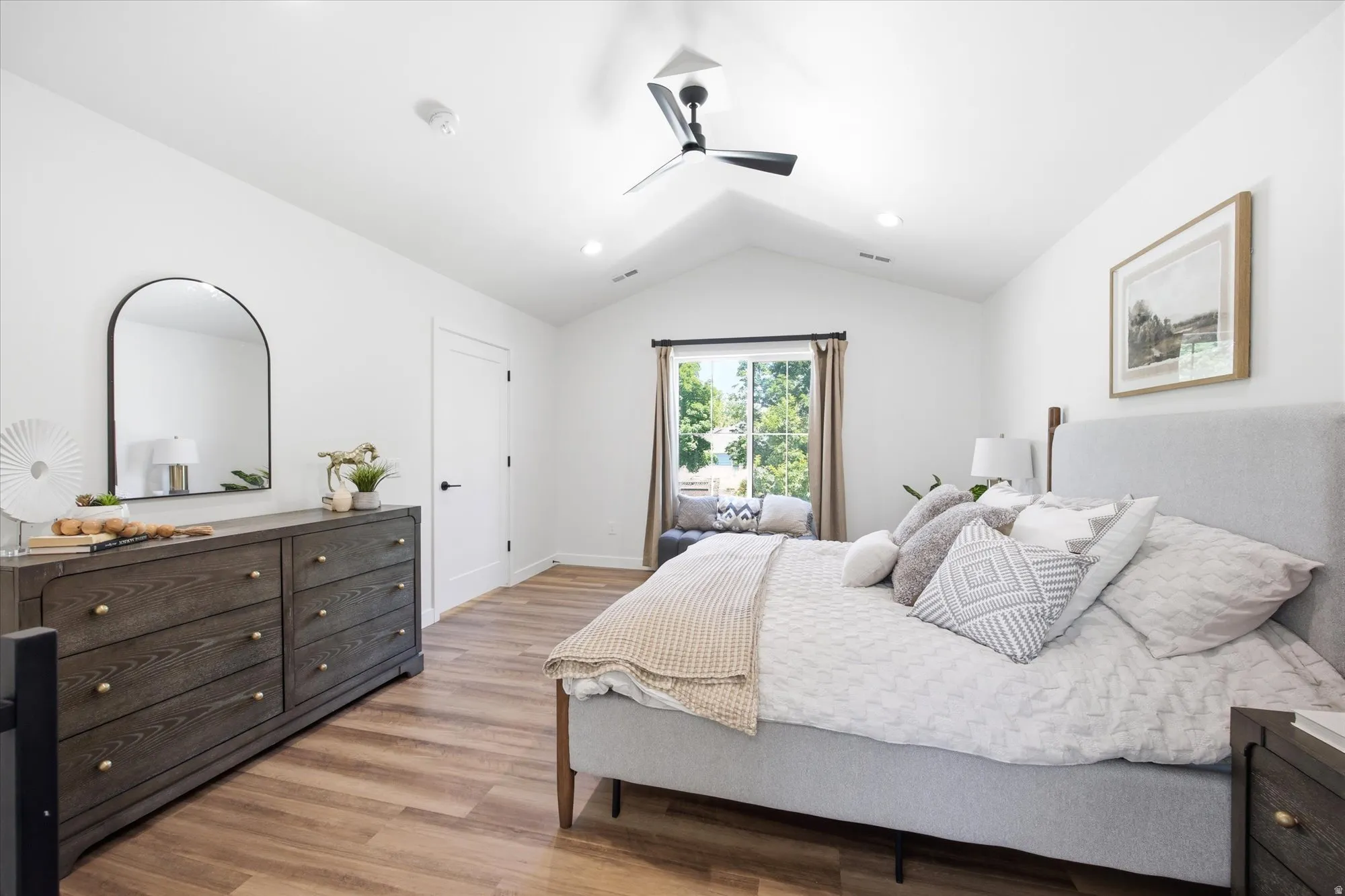 Vaulted ceiling bedroom featuring wood-finish flooring