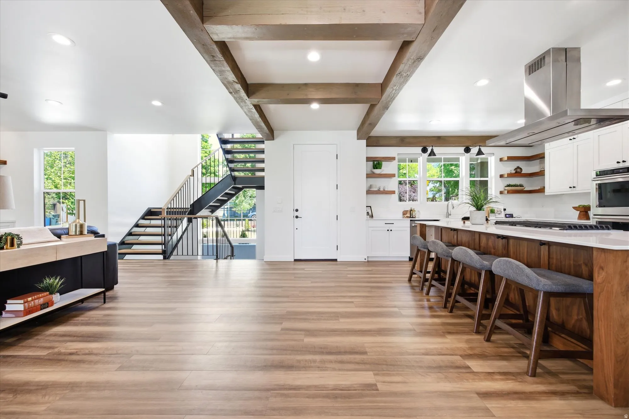 Open-concept space featuring wood-finish flooring, exposed ceiling beams, and recessed lighting