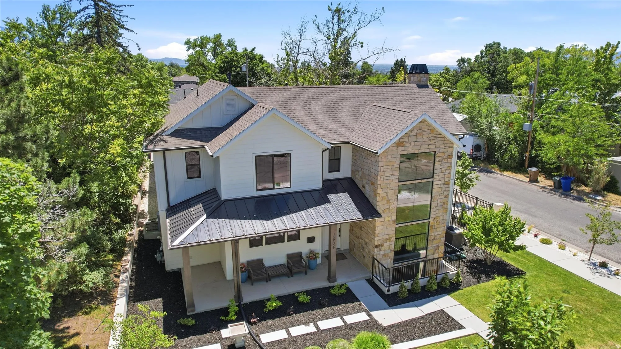 Modern farmhouse exterior with white siding, stone accents, and a dark shingle roof