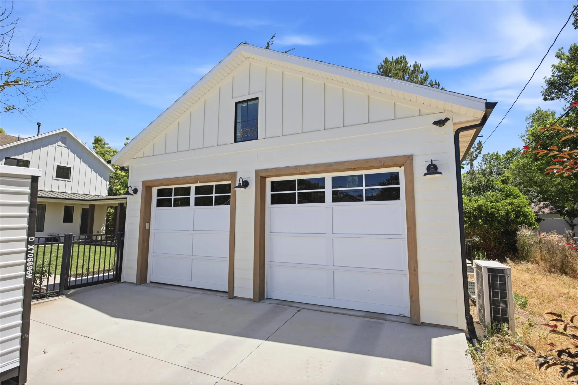 Two-car garage with modern white doors, framed by wood-finish trim and featuring upper window panels