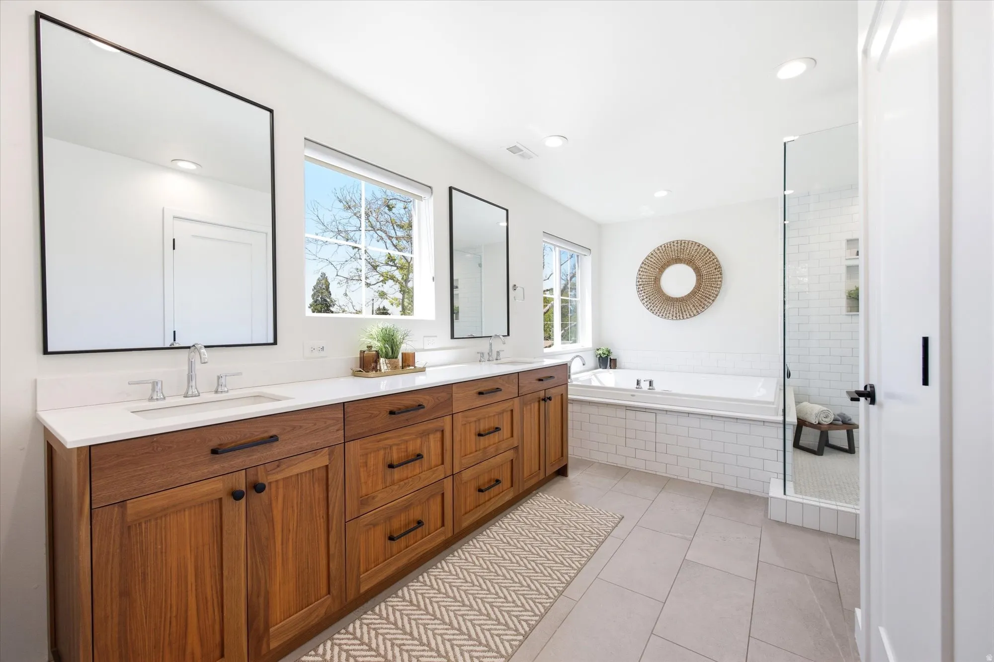 Bathroom featuring a dual wood-tone vanity with white countertops, undermount sinks, and contemporary framed mirrors