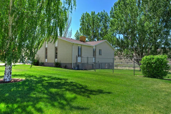 Expansive green lawn with mature trees and a chain-link fence