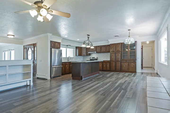 Open-concept kitchen and living area featuring wood-finish flooring, recessed lighting, and a ceiling fan