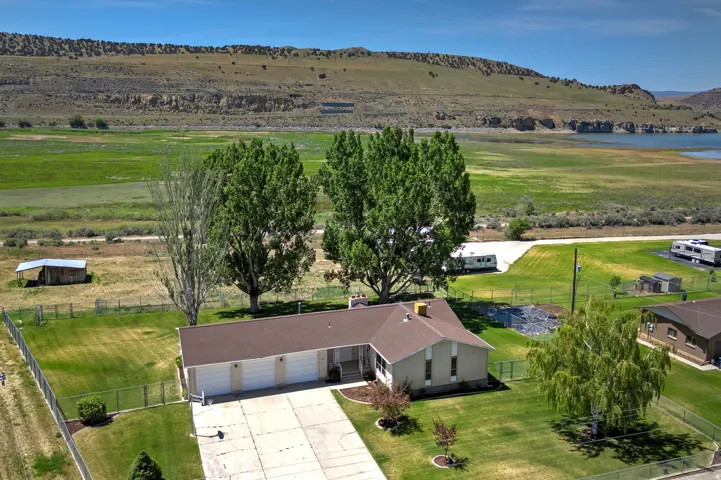 Expansive property featuring a ranch-style home with a three-car garage, established landscaping, and a fenced yard
