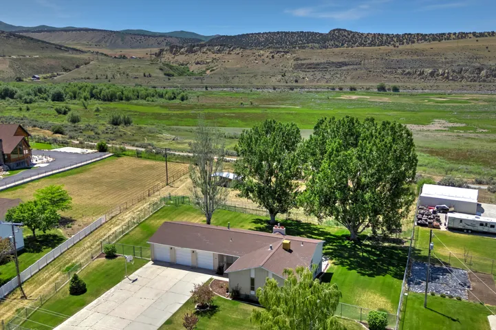 Ranch-style residence featuring a three-car garage, expansive concrete driveway, and mature landscaping