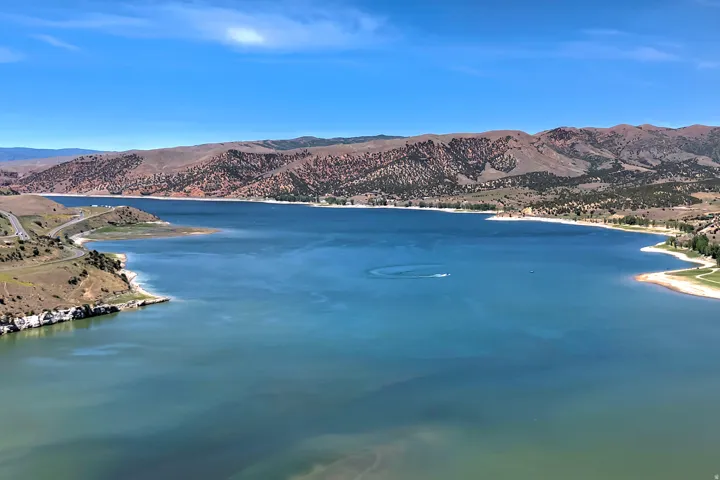 Expansive waterfront property featuring a large body of water, distant mountains, a meandering shoreline, and natural terrain
