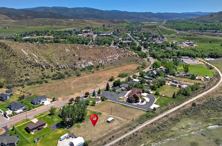 Expansive land parcel with surrounding residential properties, paved roads, and natural hillsides