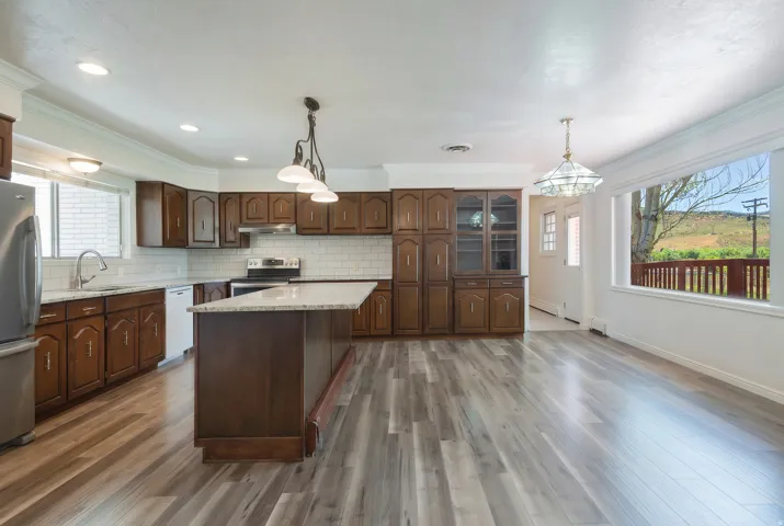 Open-concept kitchen and dining area featuring wood-finish flooring, recessed lighting, and a kitchen island with a light-toned countertop
