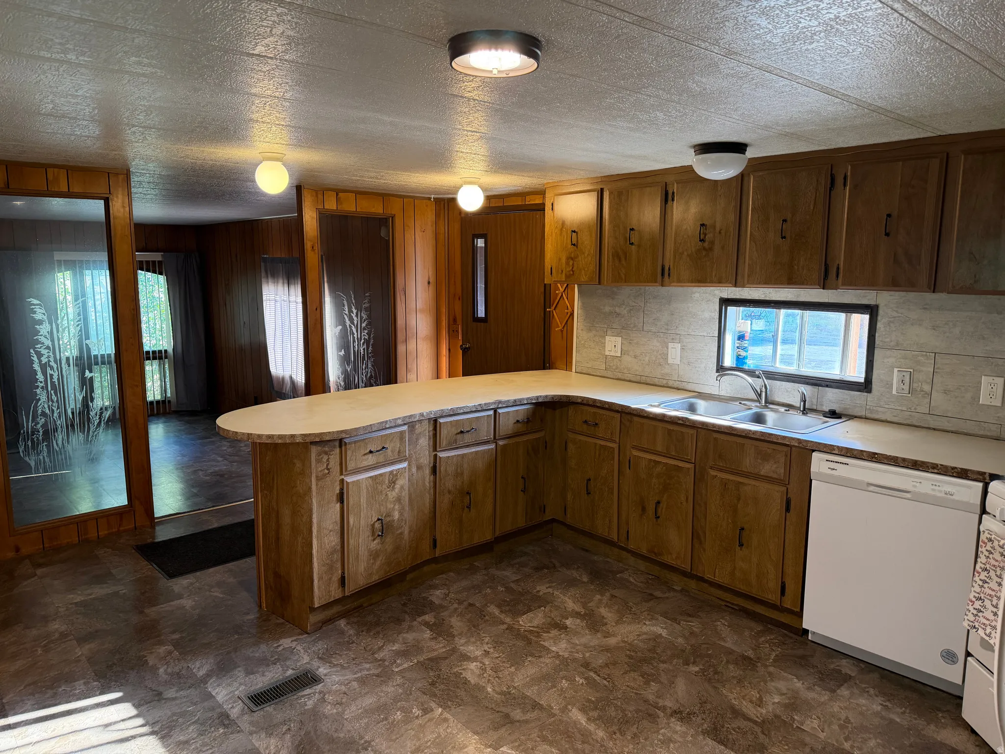 Kitchen featuring wood-finish cabinetry, a double basin stainless steel sink, and a white built-in dishwasher