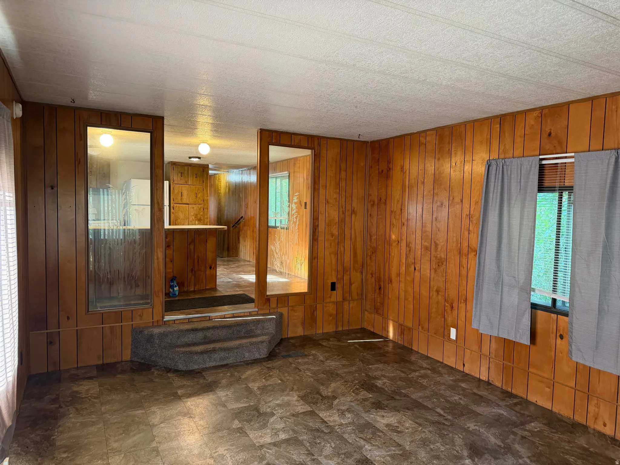 Living area featuring wood-finish paneling, patterned linoleum flooring, and a drop ceiling
