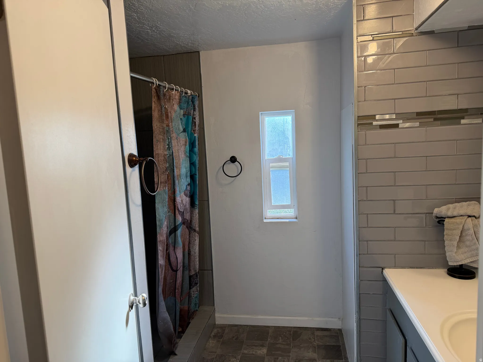 Bathroom featuring subway tile accents, a single window, and a vanity with an integrated sink