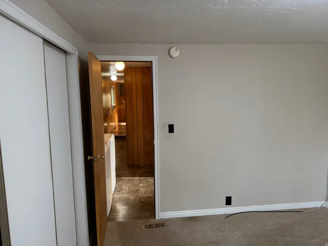 Room featuring neutral painted walls, textured ceiling, and carpet flooring