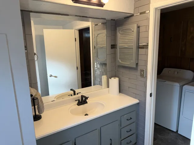 Bathroom vanity with a single basin sink, matte black faucet, and painted gray cabinetry