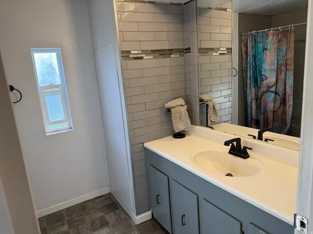 Bathroom featuring a light-colored vanity with dual sinks and a dark-toned faucet, complemented by a large wall-mounted mirror