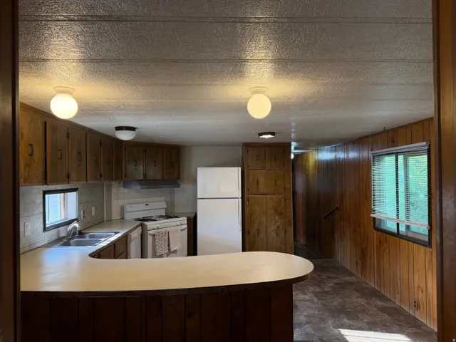 Kitchen featuring a curved breakfast bar, ample wood cabinetry, and a double basin sink