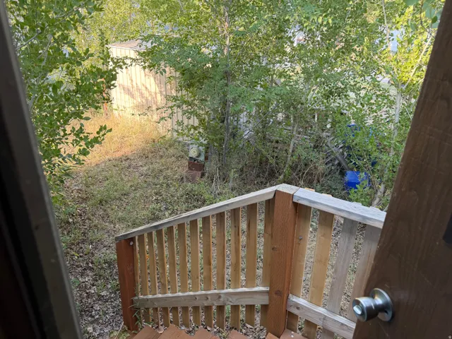 Rear wood-finish stairs with wood balusters descending to a sloped yard