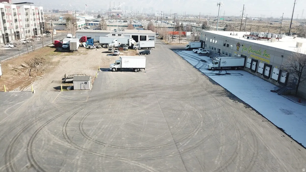Commercial building featuring multiple loading docks, a large asphalt lot, and an additional gravel yard area