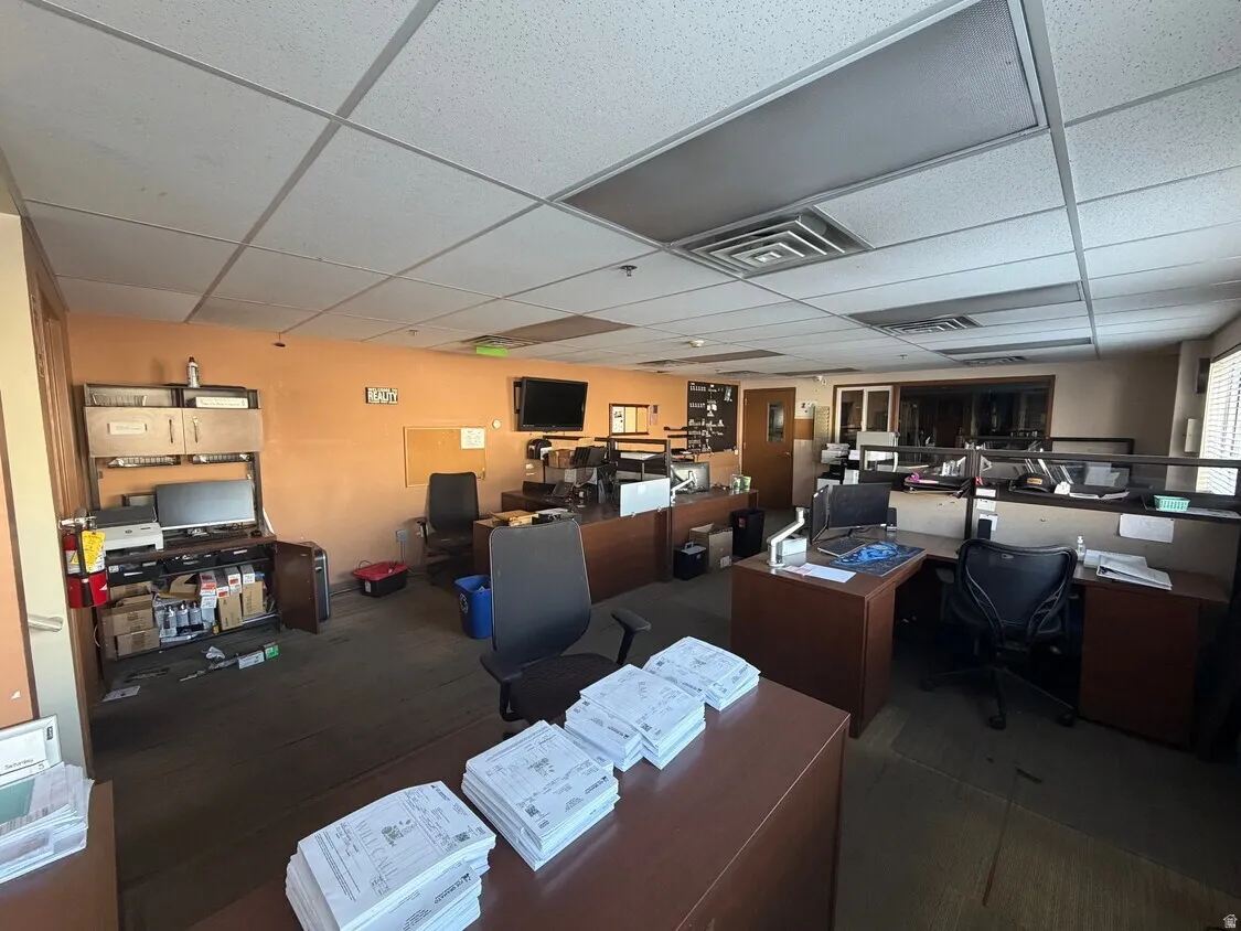 Open office space featuring drop ceiling, recessed lighting, individual workstations, and wood-finish cabinetry