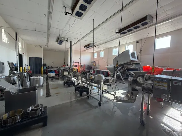 Industrial space featuring a concrete floor, multiple windows, fluorescent lighting, and commercial-grade cooling units
