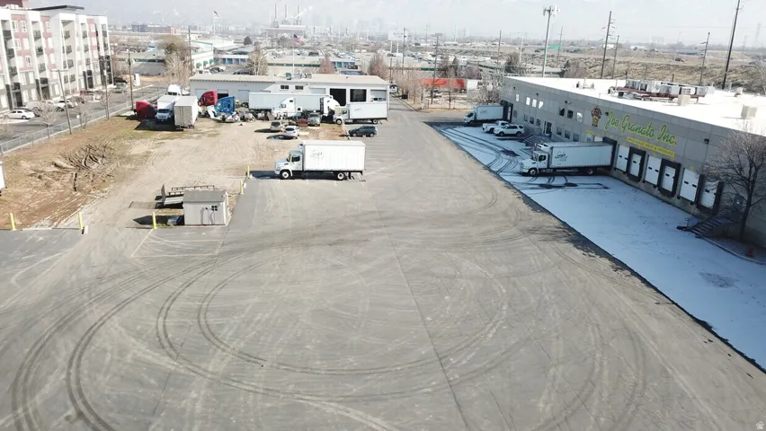 Commercial building featuring multiple loading docks, a large asphalt lot, and an additional gravel yard area