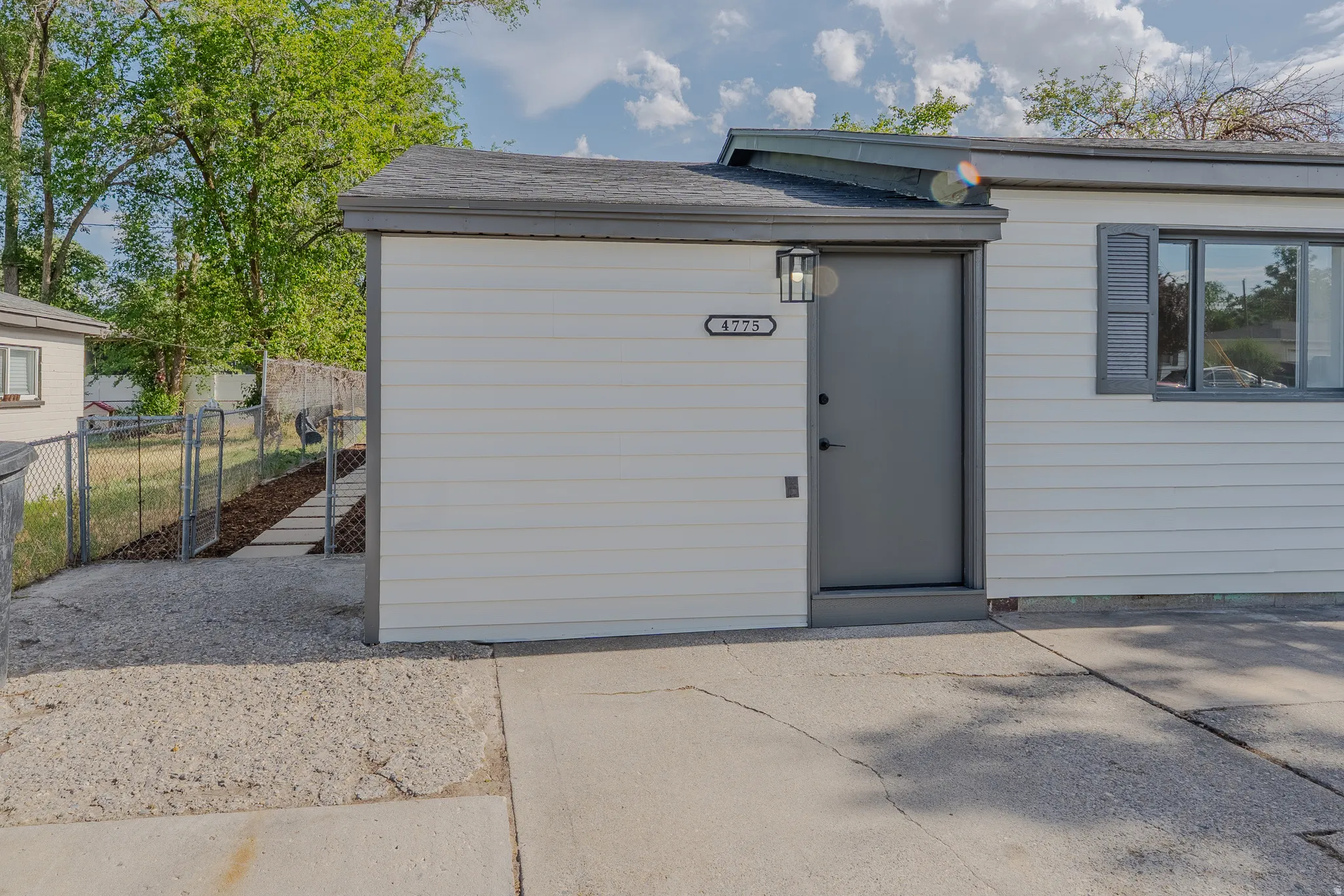 White horizontal siding facade with a dark gray entry door and coordinating window shutters