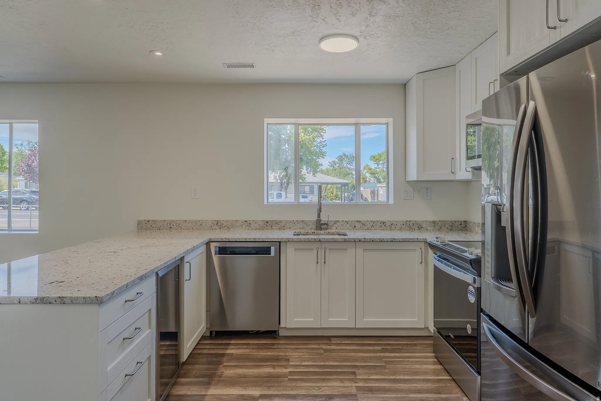 Modern kitchen with white cabinetry and wood-finish flooring