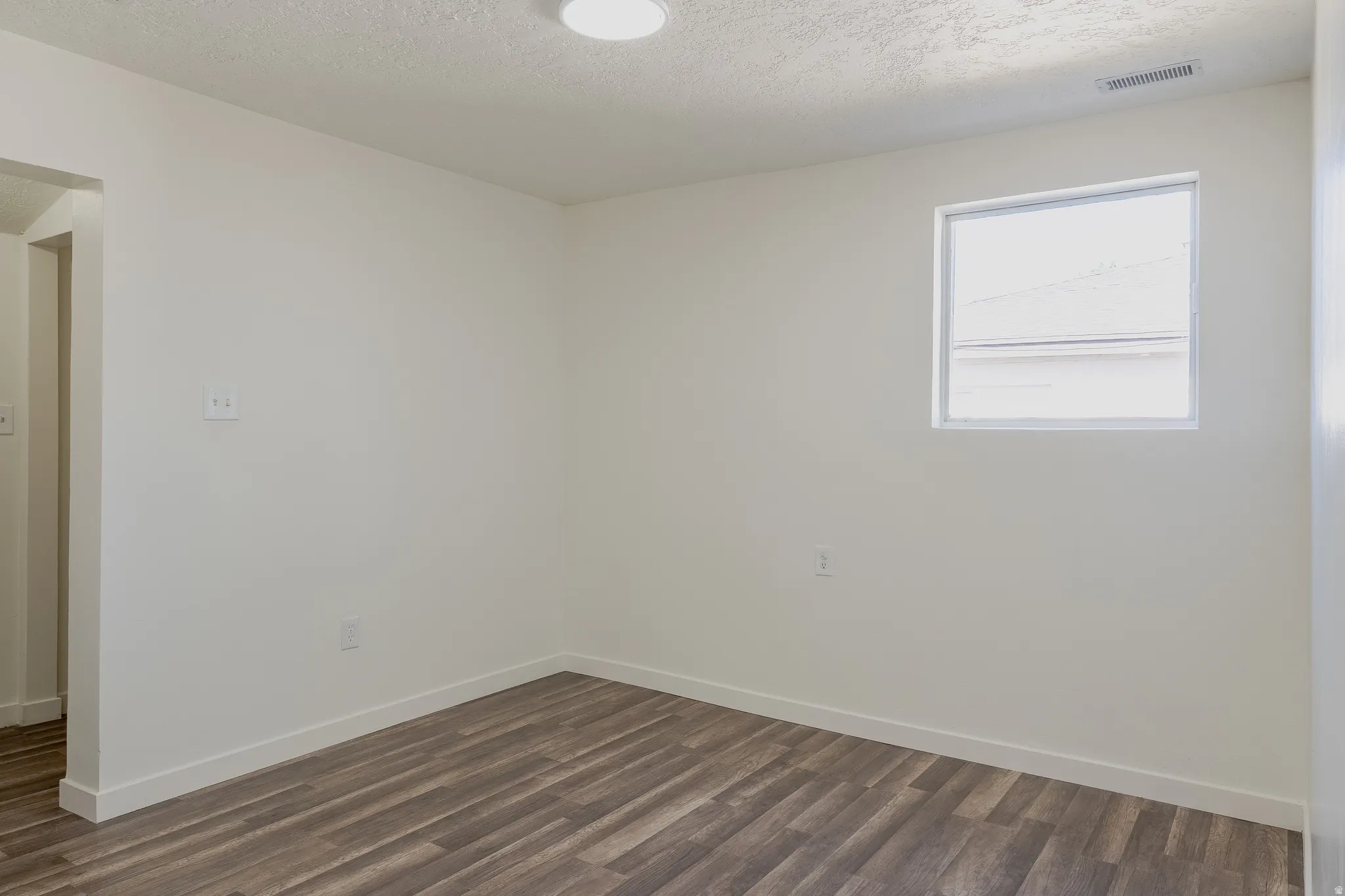 Room featuring wood-finish flooring, white baseboards, and neutral wall paint