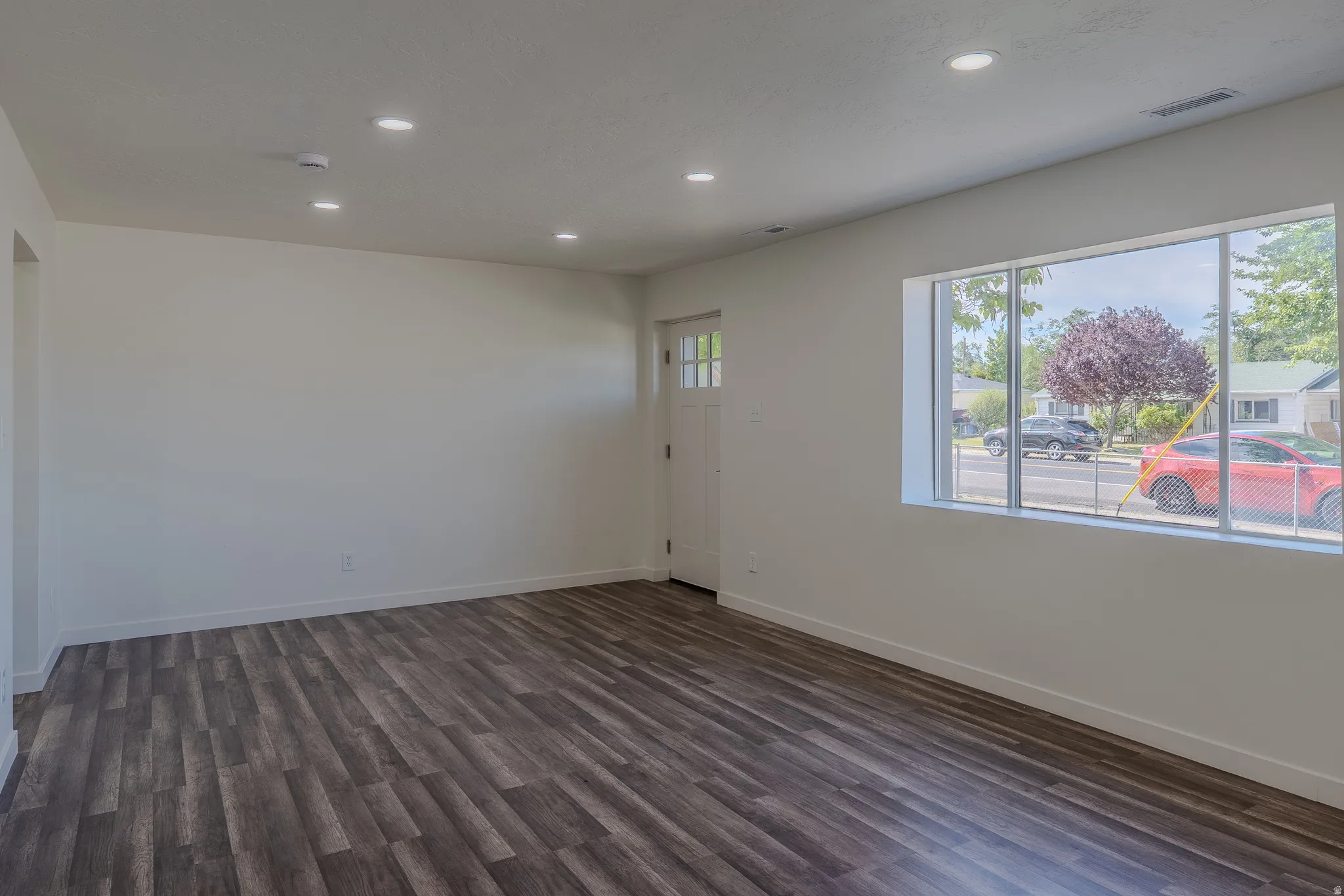 Spacious interior room featuring wood-finish flooring, recessed lighting, and a large window