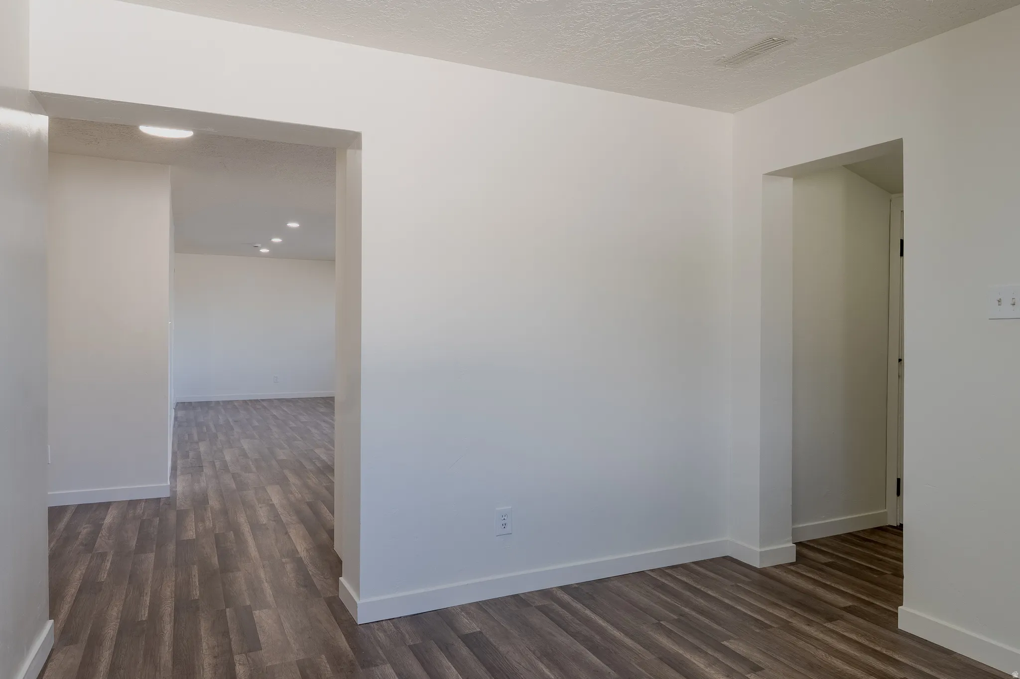 Hallway featuring wood-finish flooring, white baseboards, and neutral wall tones