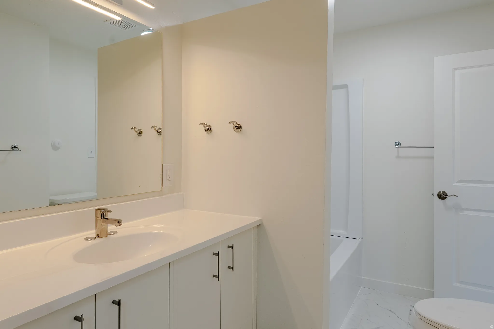 Bathroom featuring a vanity with an integrated sink, polished chrome faucet, and white countertop