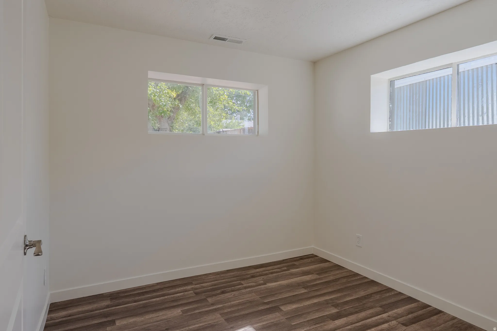 Room featuring wood-finish flooring, two windows, white walls, and white trim