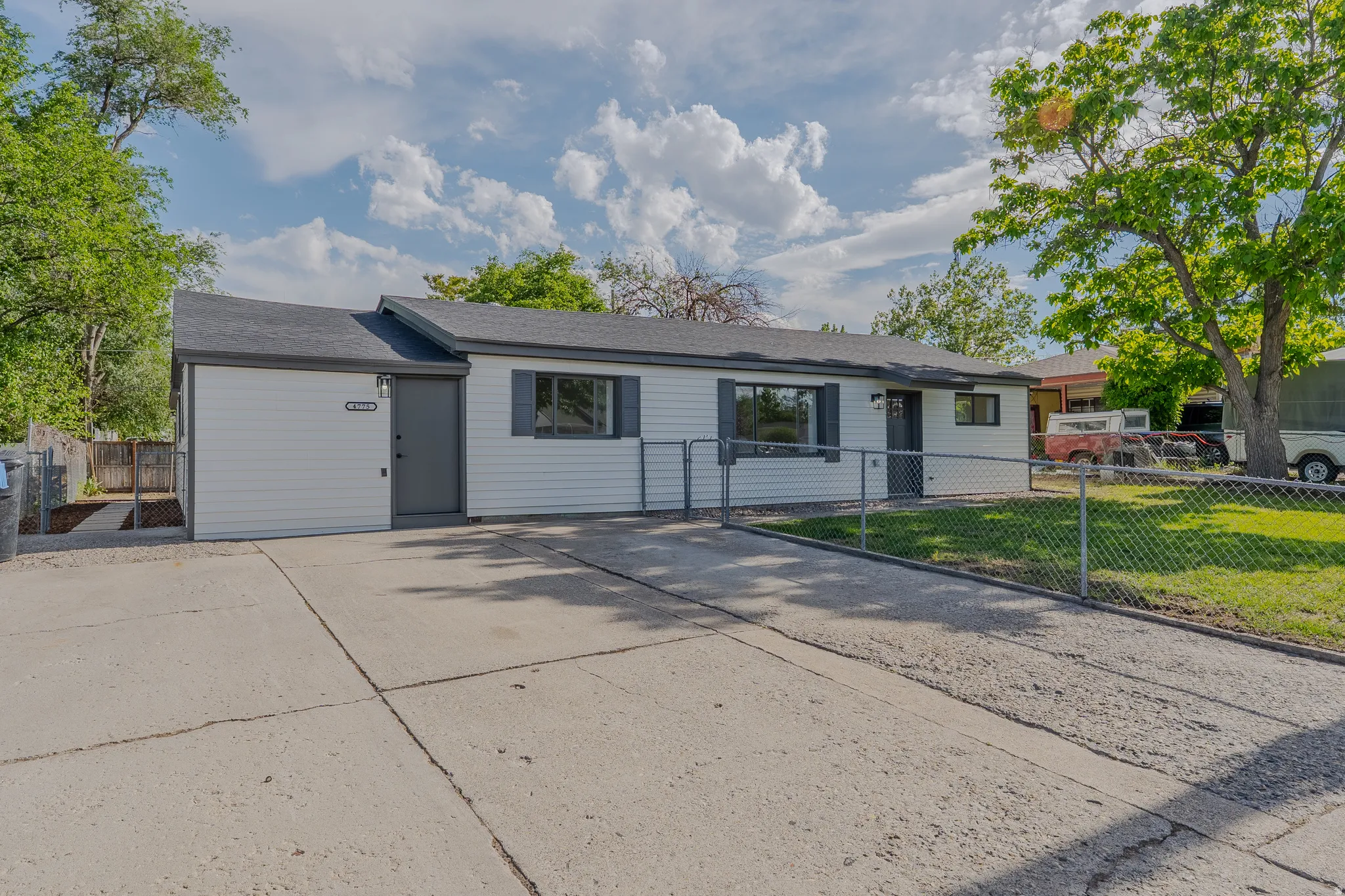 Ranch-style exterior with white siding, dark gray trim, and a dark asphalt shingle roof