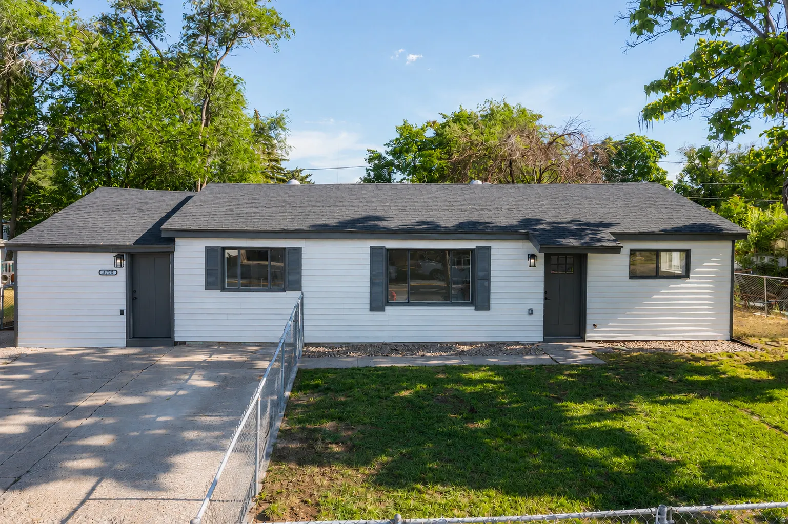 Ranch-style exterior with white siding, dark gray trim, and a dark asphalt shingle roof