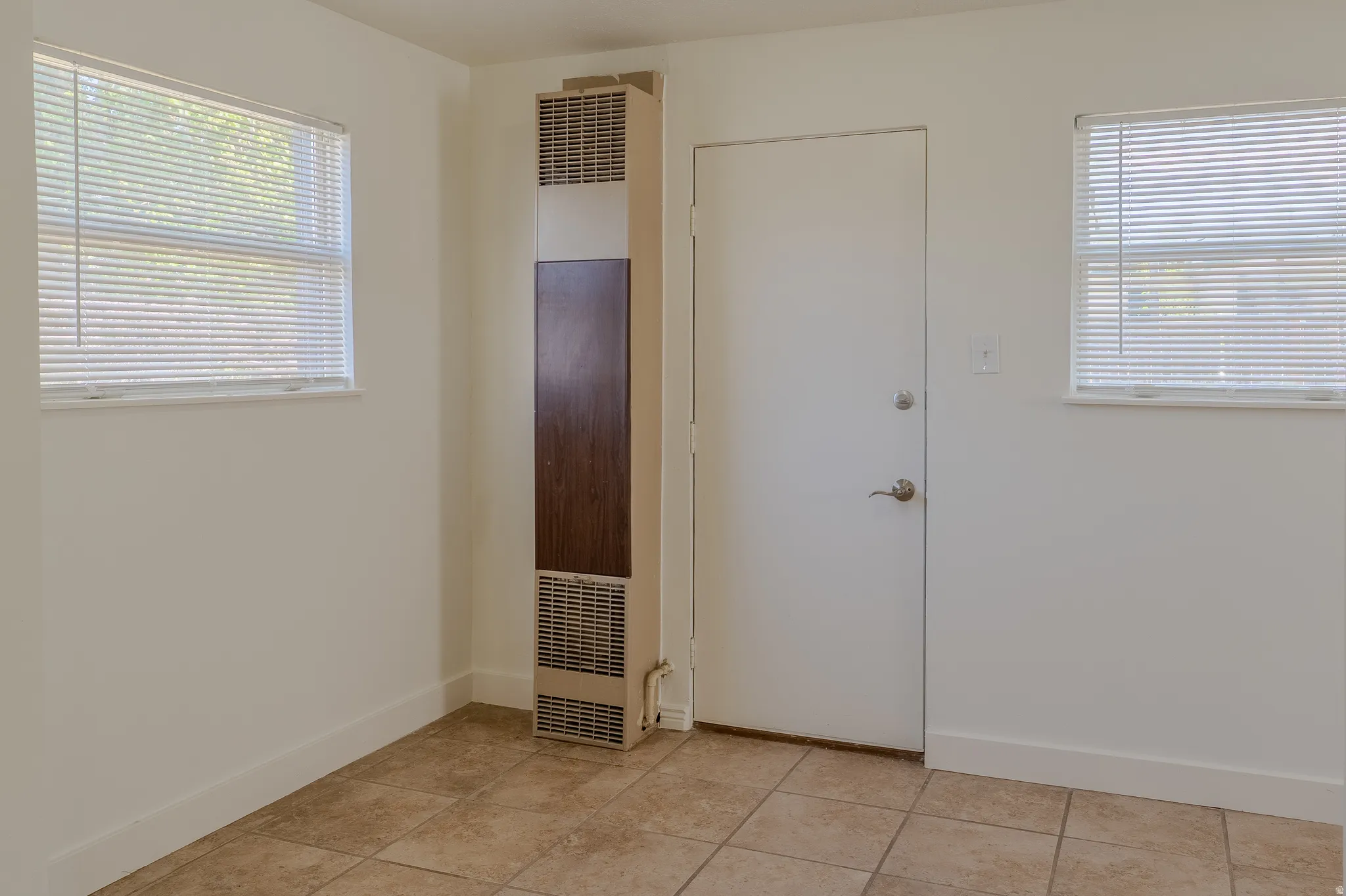 Tiled flooring accompanies a white door with a circular knob and deadbolt