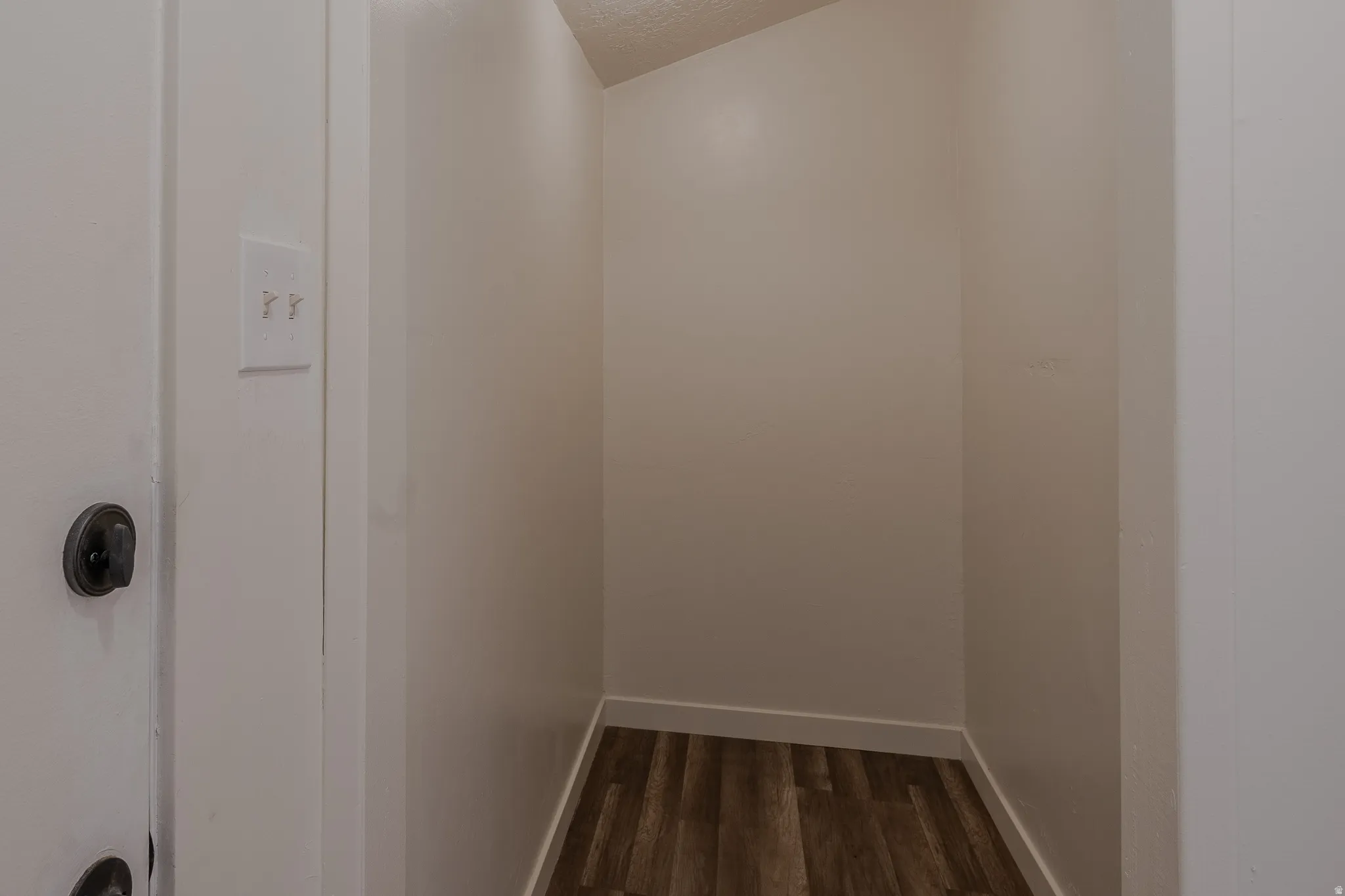 Interior storage niche with wood-finish flooring, light-colored walls, and white baseboards