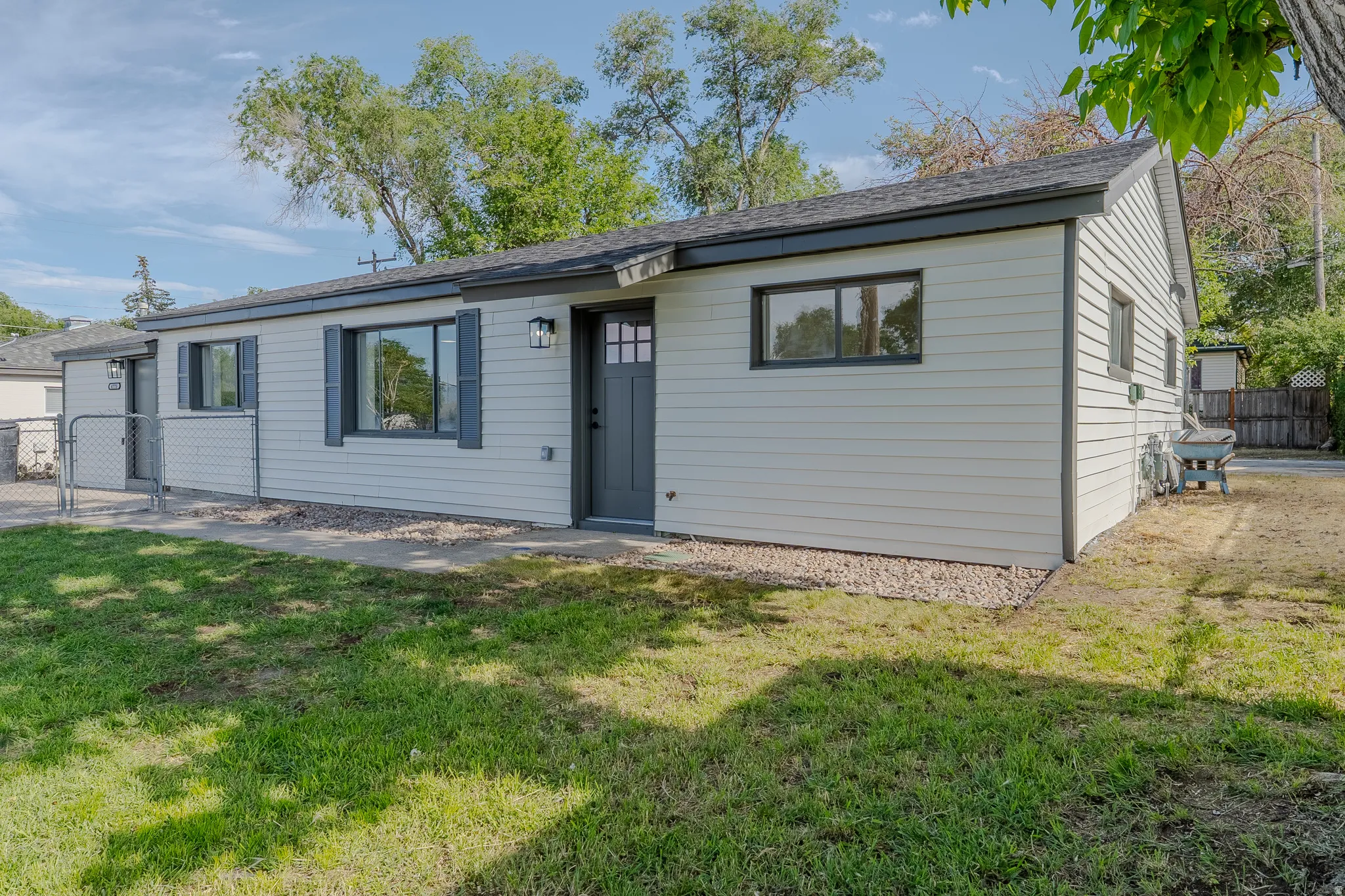 Ranch-style residence featuring light-colored horizontal siding, dark trim, and a dark front door with windowpanes