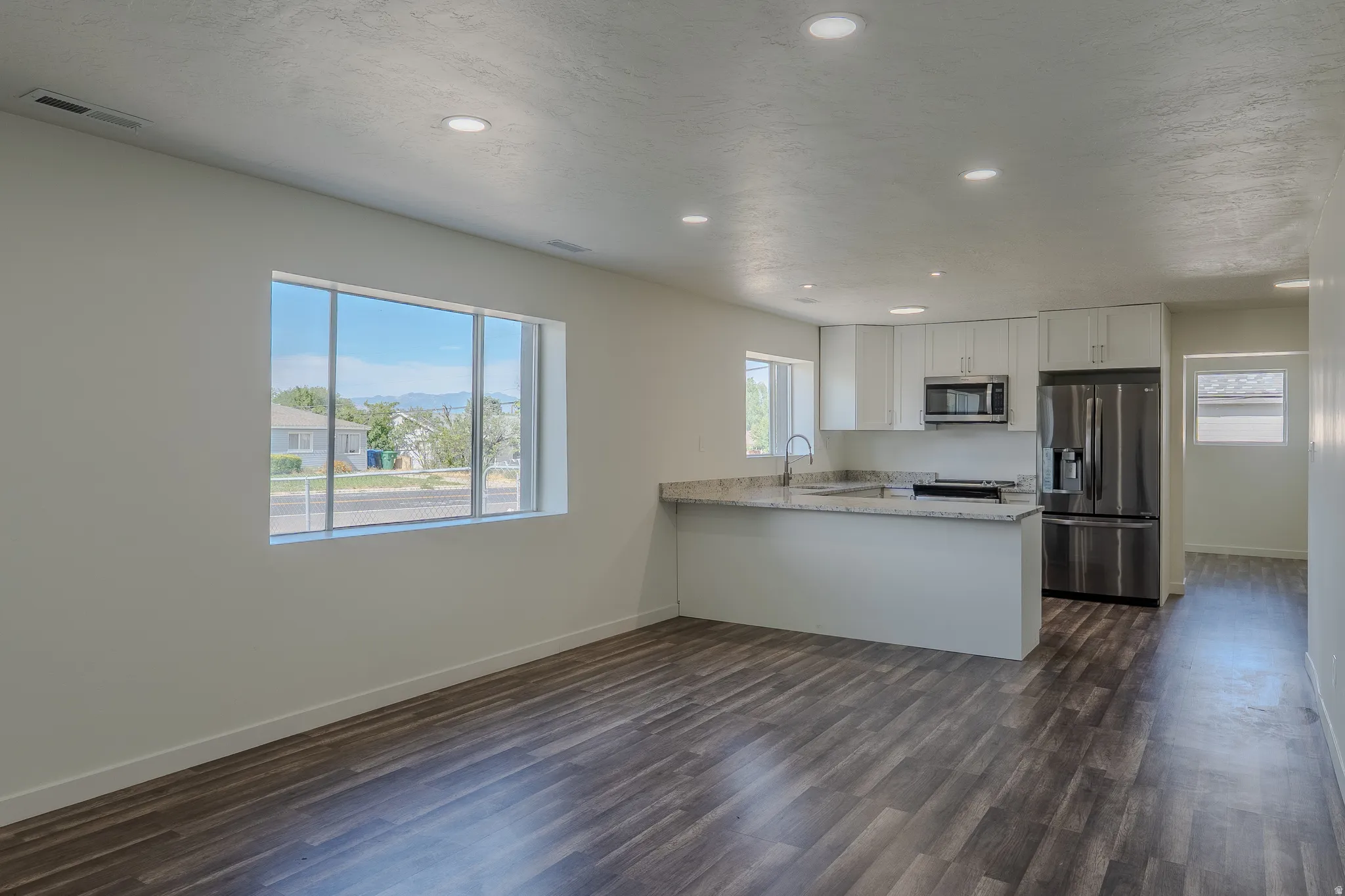 Open-concept living space with wood-finish flooring, recessed lighting, and a modern kitchen