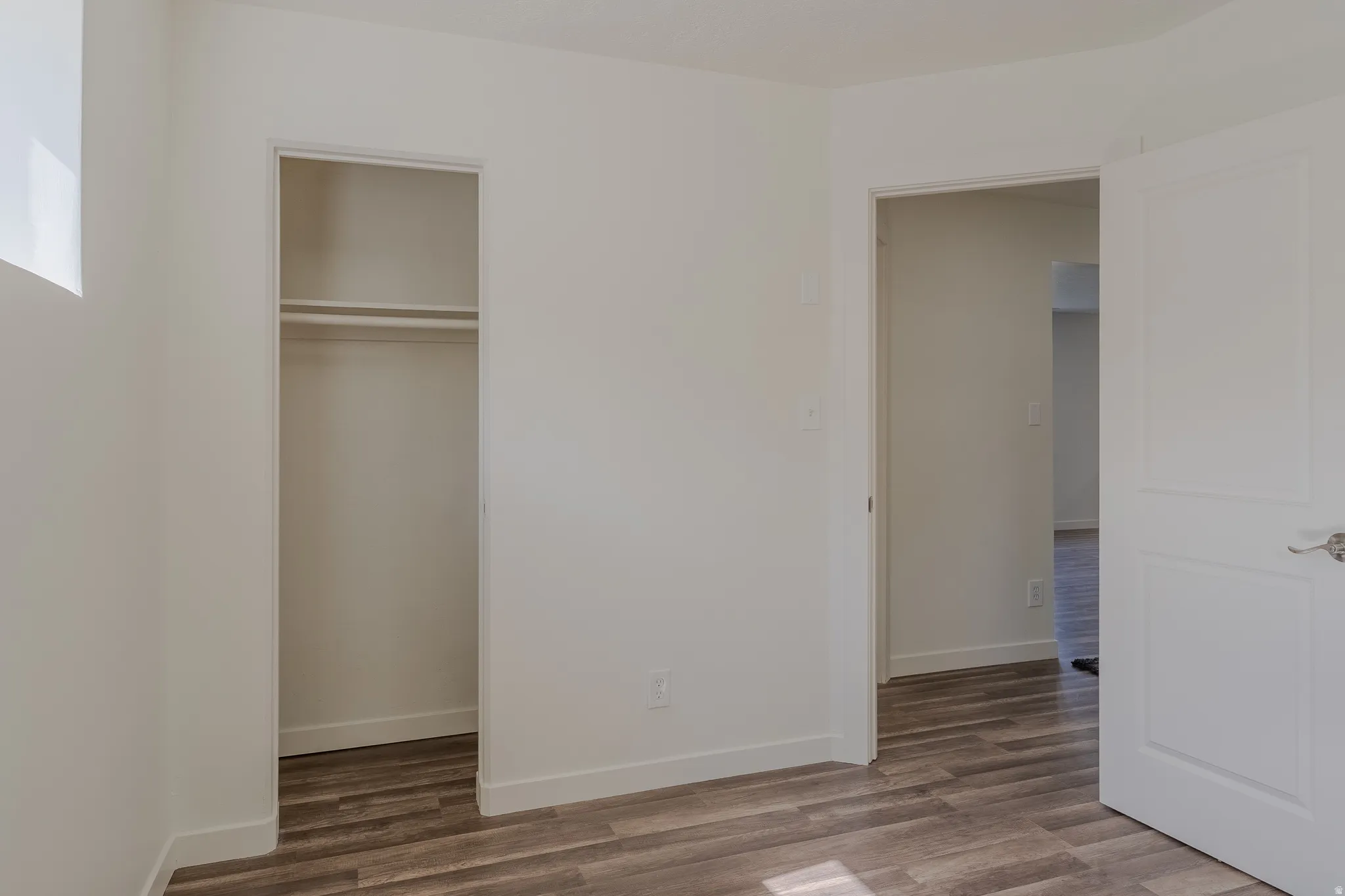 Room featuring wood-finish flooring, white baseboards, and neutral wall paint