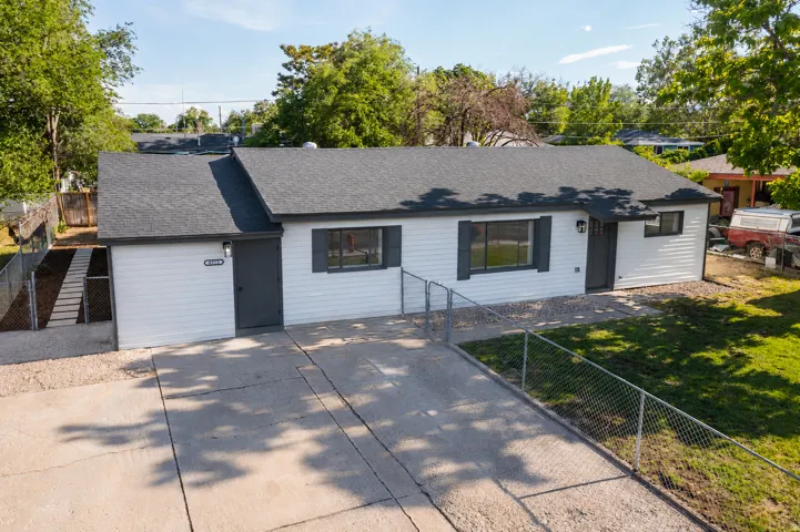 Single-story property featuring light-colored siding with dark trim, a dark asphalt shingle roof, and a concrete driveway