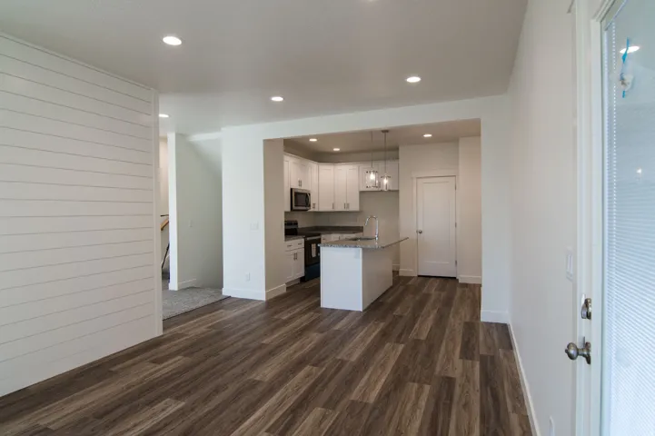 Open-concept living space featuring wood-finish flooring, recessed lighting, and a shiplap accent wall