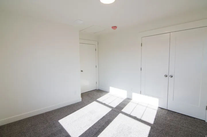 White-painted interior room with gray carpet flooring and bright overhead lighting