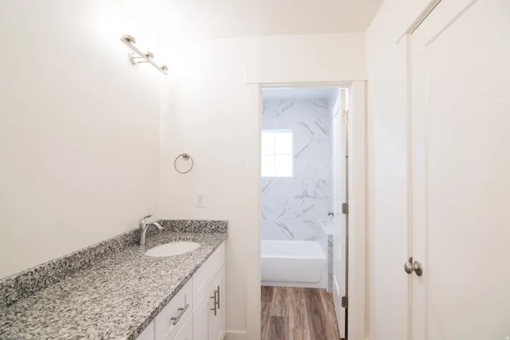Bathroom vanity featuring a speckled countertop, undermount sink, and chrome faucet