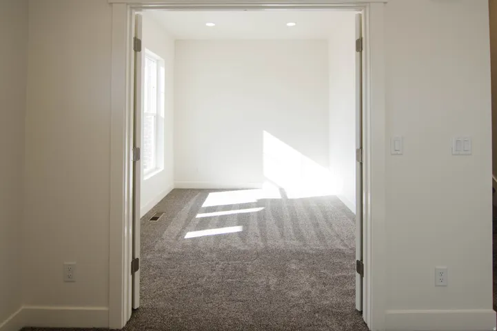 Room with neutral-toned carpeting and a single window