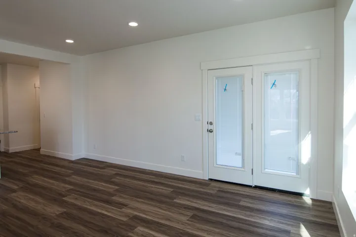 White walls with recessed lighting and wood-finish flooring