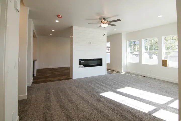 Spacious living area featuring a modern linear fireplace with shiplap surround, recessed lighting, ceiling fan, and multiple windows